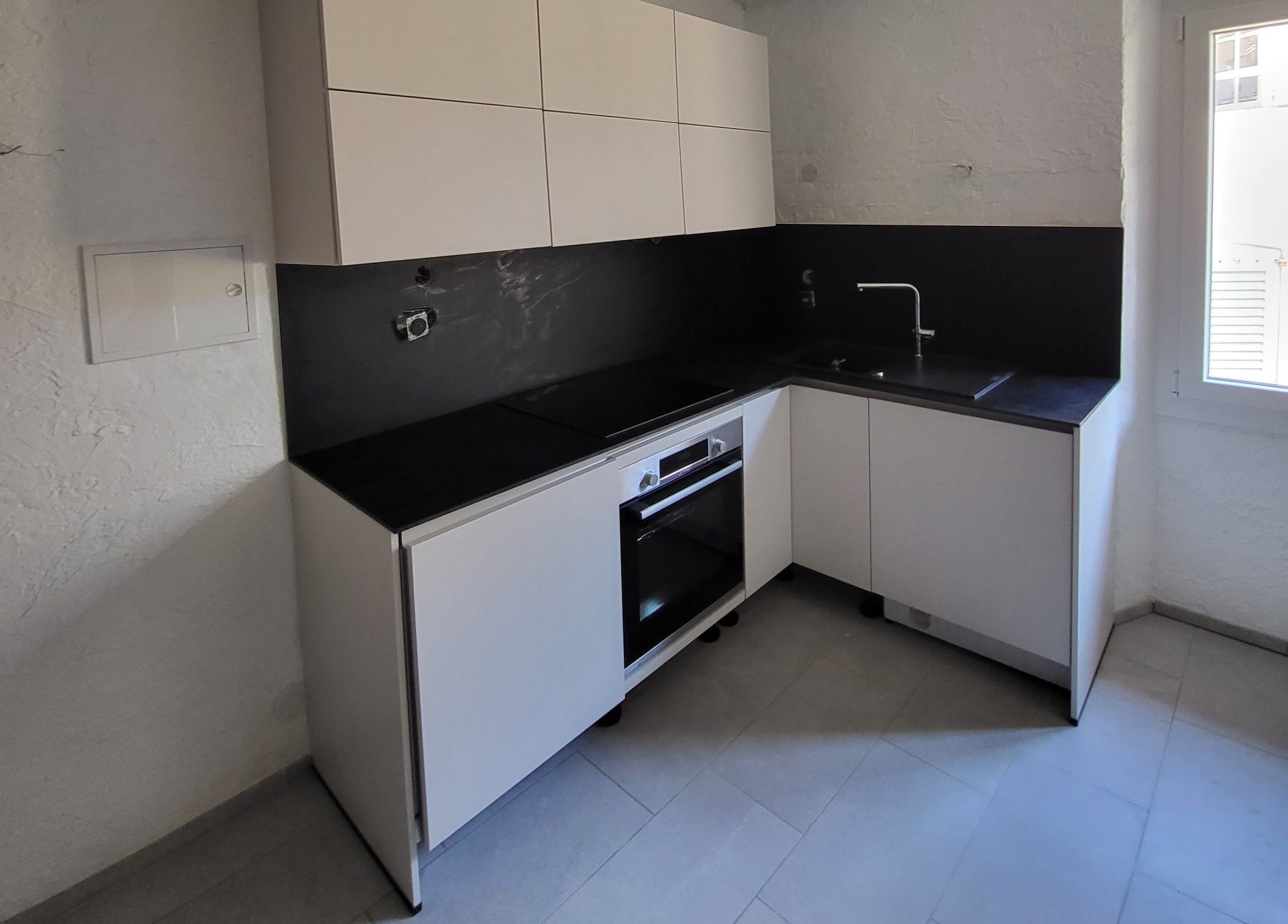 cuisine aménagée meubles de couleur blanche et plan de travail noir